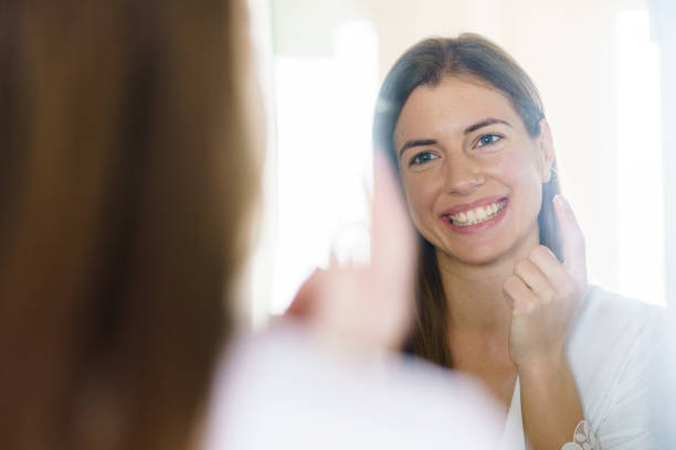 istock Woman applying face cream in front of a mirror 1432503354