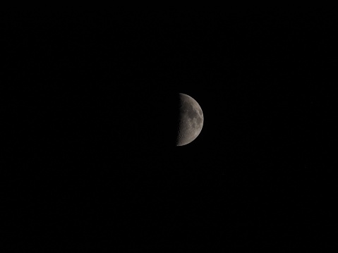 A closeup of the half moon shining in a dark night sky