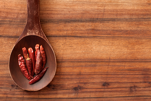 Top view of wooden spoon over table with dried chili peppers on it