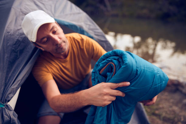 istock Man camping in nature, setting up the tent for overnight staying near forest river. 1432509604