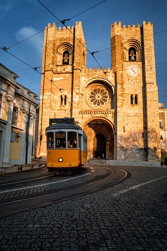 A vertical shot of the Lisbon Cathedral as a tram is passing in front of it