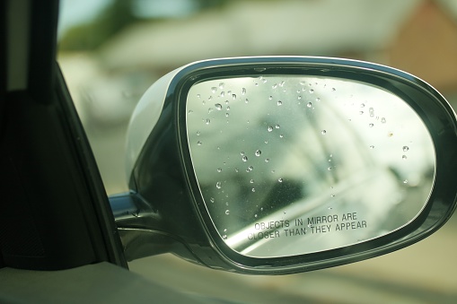 A closeup shot of a car's side-view mirror with rain drops