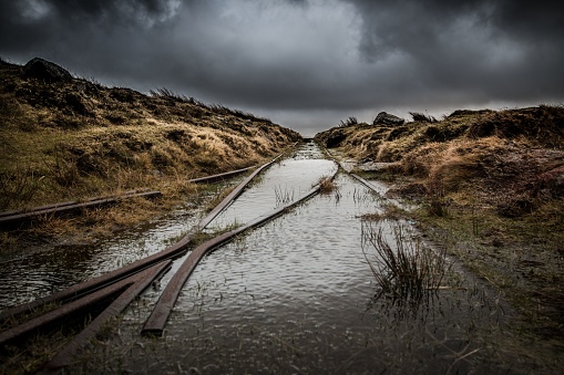 A path of damaged train rails submerged in rainwater going through an open field