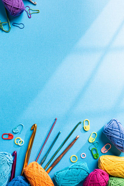 istock Crochet background with assorted colorful yarn and knit accessories over blue, top view, flat lay with copy space. Window shadow 1432514416