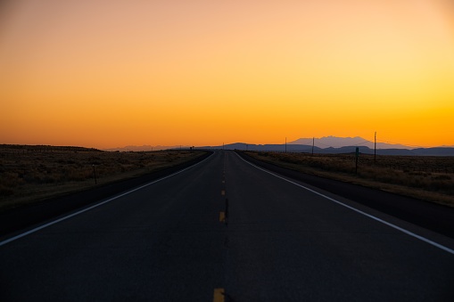 A scenic view of a highway road against the yellow sky at sunset