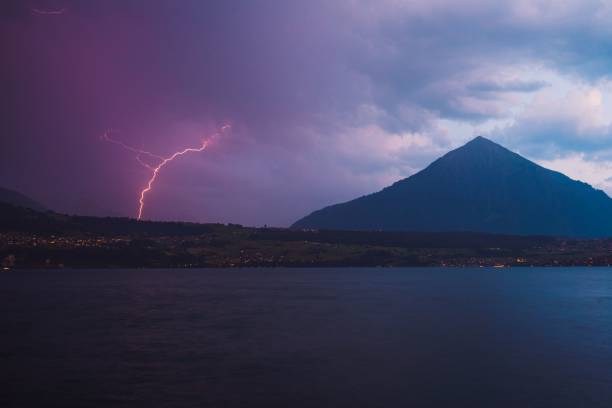 colina alta perto de um lago sob o céu nublado à noite em merligen, suíça - lake thun switzerland night lake - fotografias e filmes do acervo