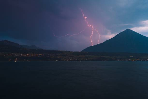 colina alta perto de um lago sob o céu nublado à noite em merligen, suíça - lake thun switzerland night lake - fotografias e filmes do acervo