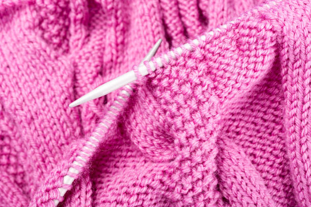 Background with knitting pink wool sweater in progress. top view. Knit a Braid Cable