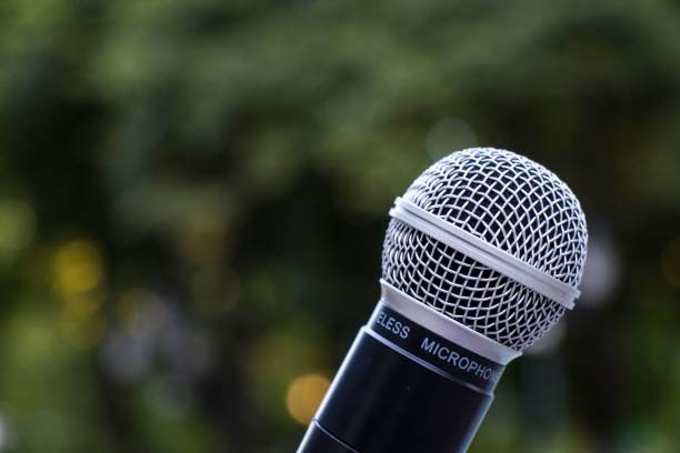 istock Closeup of a microphone against green trees 1432516561