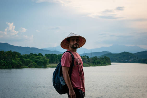 Tourist with Vietnamese hat enjoying the views of the Perfume River in Hue, Vietnam. Beautiful view of the Perfume River, Hue, Vietnam. Tourist man in Hue, Vietnam. Vacation in Hue, Vietnam. Copyspace.