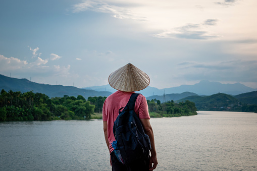 Tourist with Vietnamese hat enjoying the views of the Perfume River in Hue, Vietnam.