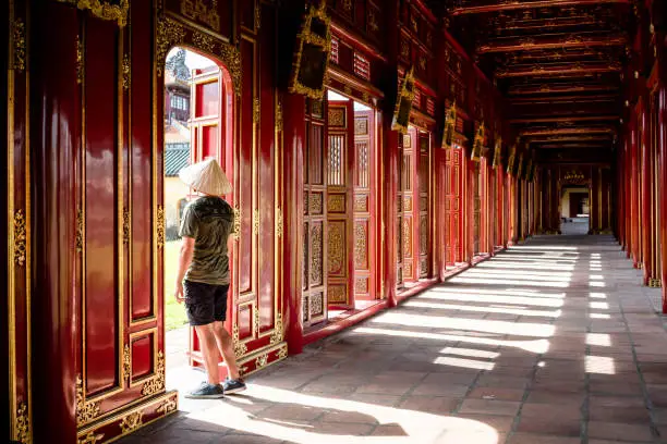 Tourist touring the Imperial City of Hue, Vietnam.  Tourist looking through the gates of the imperial city of Hue, Vietnam. Beautiful architecture of the Imperial Citadel in Hue, Vietnam.