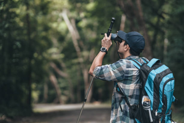 istock Hikers use binocular to see animals and view landscape  with backpacks walking through on the road in the forest. hiking and adventure concept. 1432518329