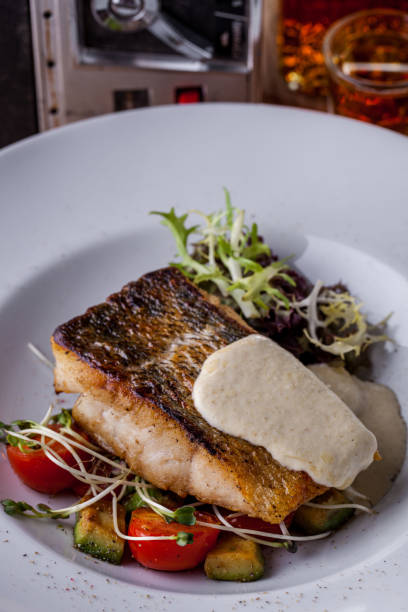 istock Fried sebasse with mashed potatoes, frize salad, young shoots, cherry tomatoes on a white round plate. Vertical orientation 1432518444