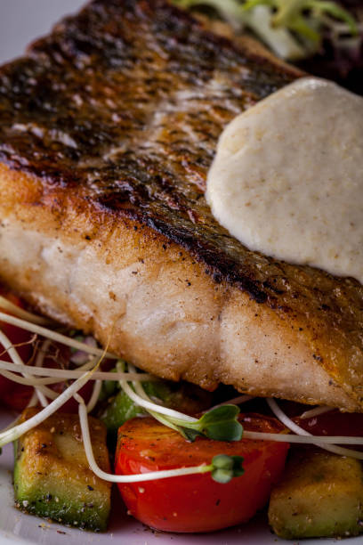 istock Fried sebasse with mashed potatoes, frize salad, young shoots, cherry tomatoes on a white round plate. Vertical orientation 1432518474