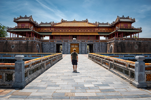 Young man at the gates of the imperial city of Hue, Vietnam. Tourist in Hue, Vietnam. Ancient stone gate of the imperial city of Hue, Vietnam. Happy tourist in Vietnam. Old gate of the imperial city of Hue.  Famous entrance to the imperial city of Hue, Vietnam