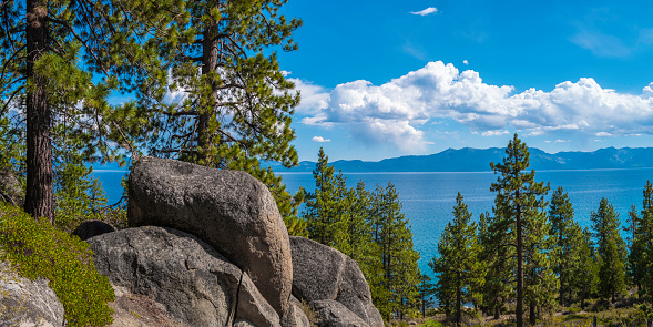 Tranquil Lake Tahoe landscape with pine trees, clean blue water, dramatic clouds, and glacial rocks and boulders in Logan Shoals Vista Point in Nevada