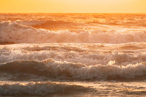 Sea water surface at sunset. Natural sunrise warm colors of ocean. Sea ocean water surface with foaming small waves at sunset. Evening sunlight sunshine above sea. Amazing landscape scenery. Nature background.