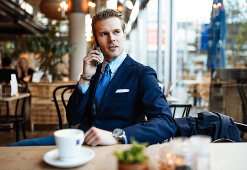 Successful businessman in full suit working remotely from cafe or coworking space