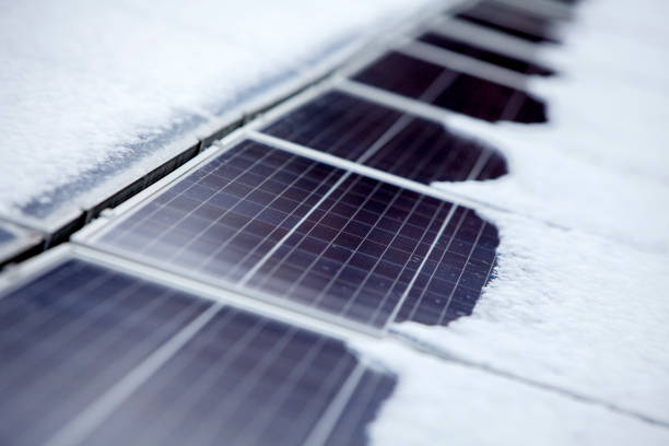 close up roof area of a solar paneled house in winter with snow on top. energy efficiency and maintenance concept. - solar panel solar power station house roof imagens e fotografias de stock