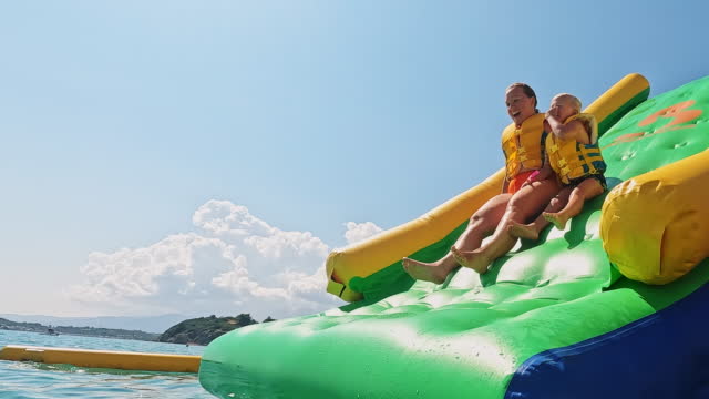 Happy Mother and Son Sliding Down an Inflatable Game