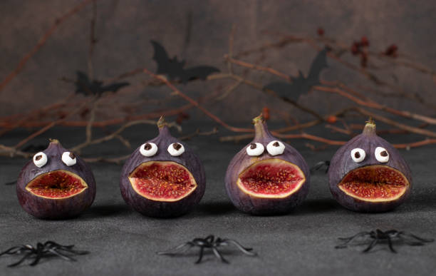 istock Spooky fig monsters for Halloween party on brown background decorated with spiders and bats 1432525599