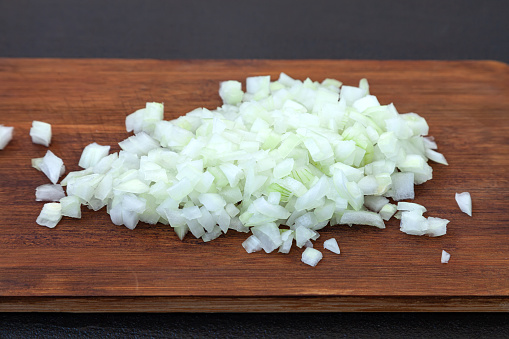 Raw onion, chopped very small cubes on a wooden board