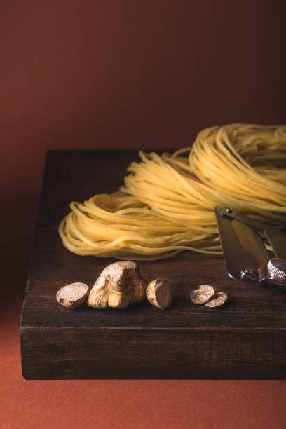 white truffle. the famous delicacy white truffle on antique board with truffle knife and pasta tajarin. terracotta background, magical light in the style of the chef's table - truffle tuber melanosporum mushroom 個照片及圖片檔