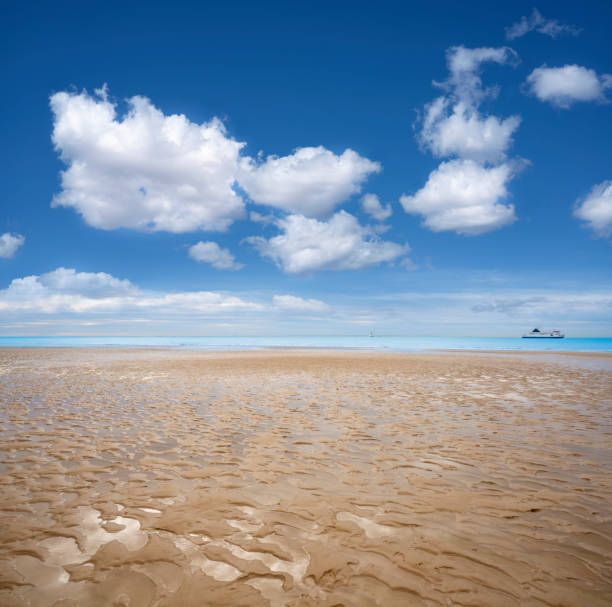 Calais beach France in low tide with wet sand dunes textures Calais beach France in low tide with wet sand dunes textures and Ferries to Dover on the sea. ferry dover england calais france uk stock pictures, royalty-free photos & images