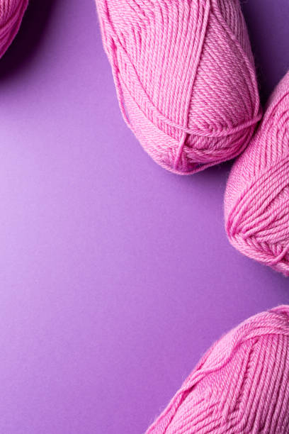 istock Knitting background with pink wool yarn balls over lilac, top view, flat lay with copy space 1432535048