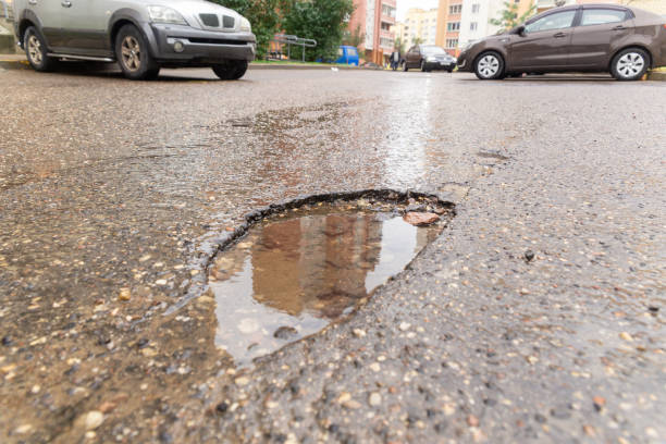 istock Water filled pot hole in the road. 1432541038