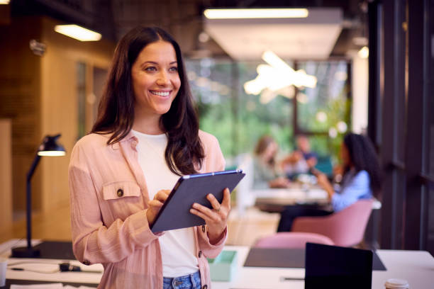 istock Smiling Businesswoman Standing In Modern Open Plan Office Using Digital Tablet 1432541130