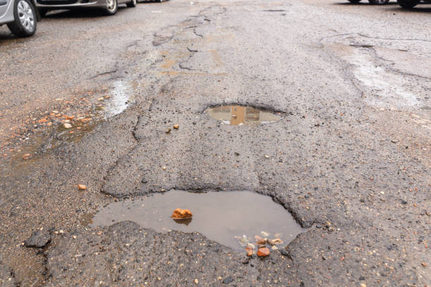 istock Water filled pot hole in the road. 1432541410