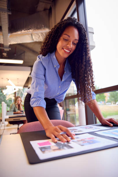 istock Businesswoman Standing At Table In Open Plan Office Approving Or Checking Proofs Or Design Layouts 1432541431