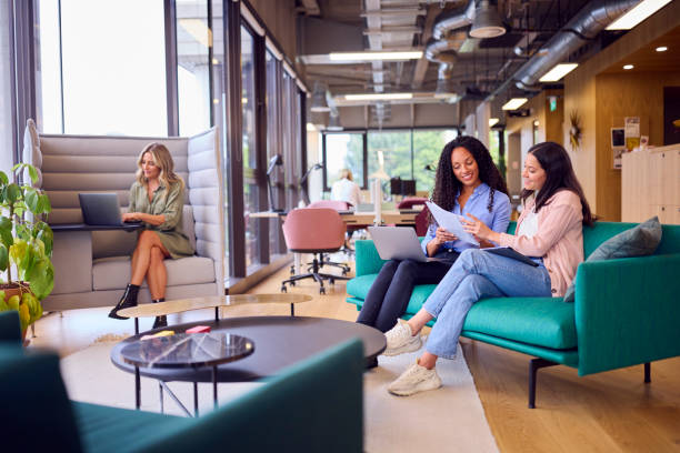 mujeres de negocios que tienen una reunión informal en el área de asientos de la oficina moderna - oficina de plan abierto fotografías e imágenes de stock