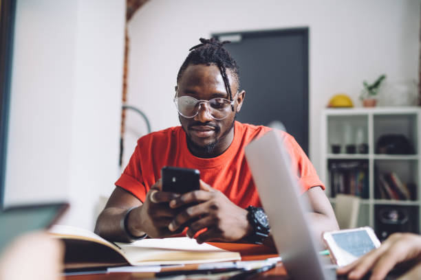 istock Young casual man sitting at table and using smartphone 1432544018