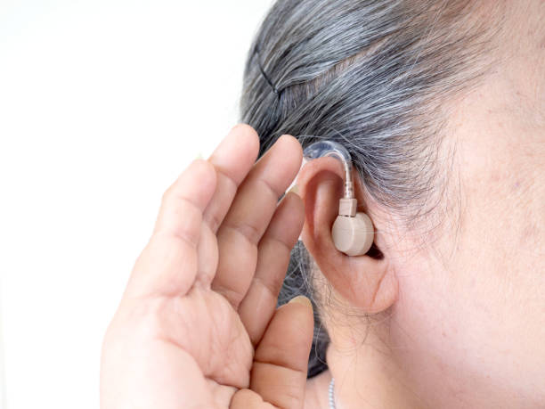 Elderly woman wearing a hearing aid Elderly woman wearing a hearing aid A picture of a person wearing a hearing aid device, which is a device used to amplify sound for people with hearing loss stock pictures, royalty-free photos & images