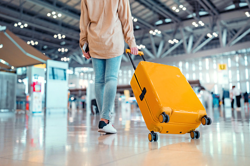 Joven viajera pasajera caminando con una maleta amarilla en la moderna Terminal del Aeropuerto, Mujer en camino a la puerta de embarque del vuelo, Listo para viajar o viaje de vacaciones photo