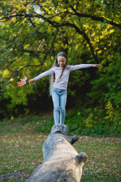 istock A girl balances on a fallen log with a leaf in her hand. 1432551043