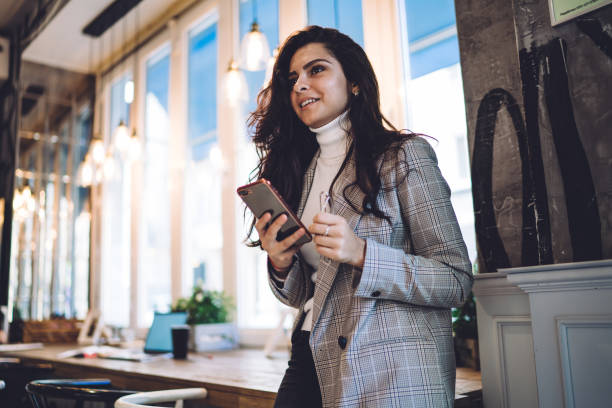 istock Smiling lady surfing cellphone in cafe 1432552887