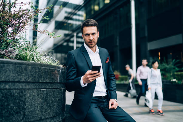istock Handsome businessman watching smartphone resting in street 1432553300