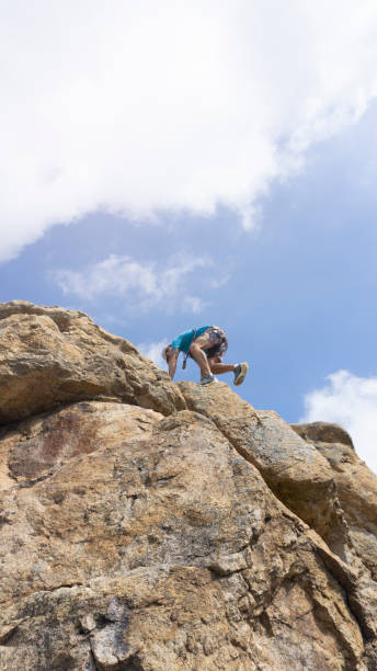 istock low view of man climbing on rock with blue sky in background . copy space 1432554068