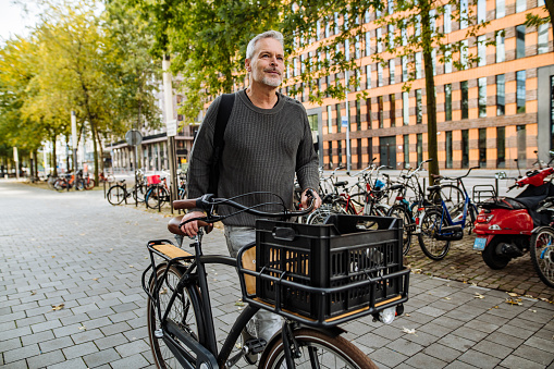 Portrait of mature or senior man in the modern city, commuting to work by bicycle