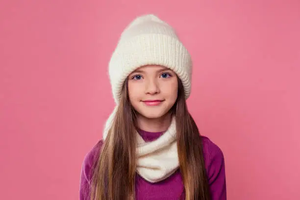 Photo of Portrait of young pretty smiling teenager girl in cold weather dressed in color clothes and warm white hat. Young happy woman autumn winter clothes seasonal sale