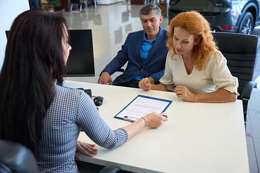 Customers communicate with the dealership manager at the office desk, they get acquainted with the documents for buying a car