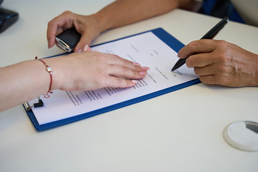 Process of signing documents on the purchase and sale of a car, the manager indicates the place of signature