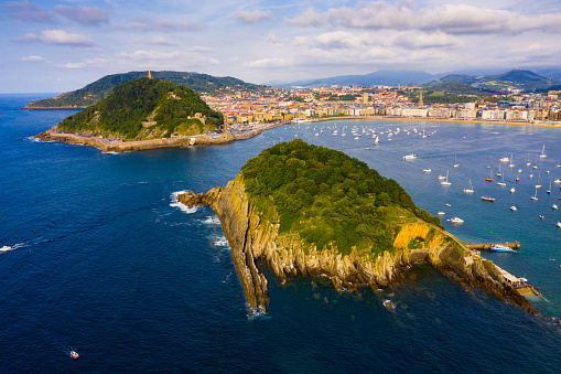 Picturesque aerial view of turquois water of La Concha Bay of San Sebastian with Santa Clara Island and moored pleasure yachts, Spain