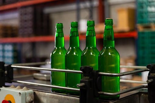 Close up of green glass unlabeled bottles of cider on bottling line