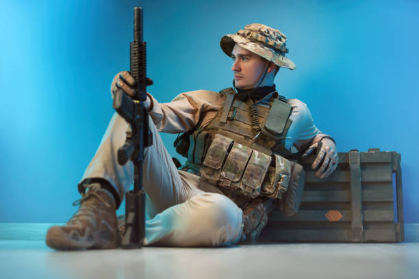 um soldado homem em camuflagem está sentado por uma caixa de munição no chão com uma arma - marines camouflage camouflage clothing male - fotografias e filmes do acervo