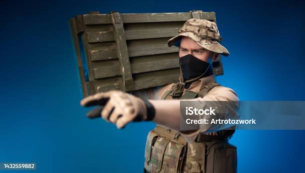 An Army Soldier In Military Clothes With A Box Of Ammunition On His Shoulder Stock Photo - Download Image Now